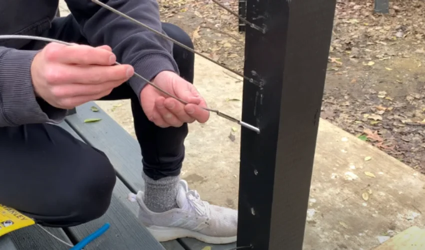  A man inserts the cable railing into the hardware