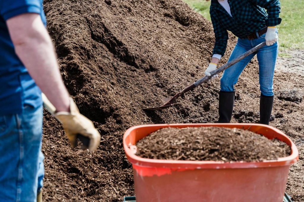 A Person Holding a Shovel while Shoveling the Soil