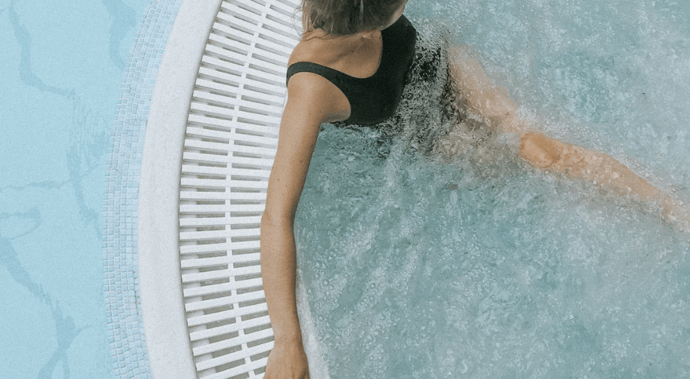 a woman relaxing in a jacuzzi next to a pool