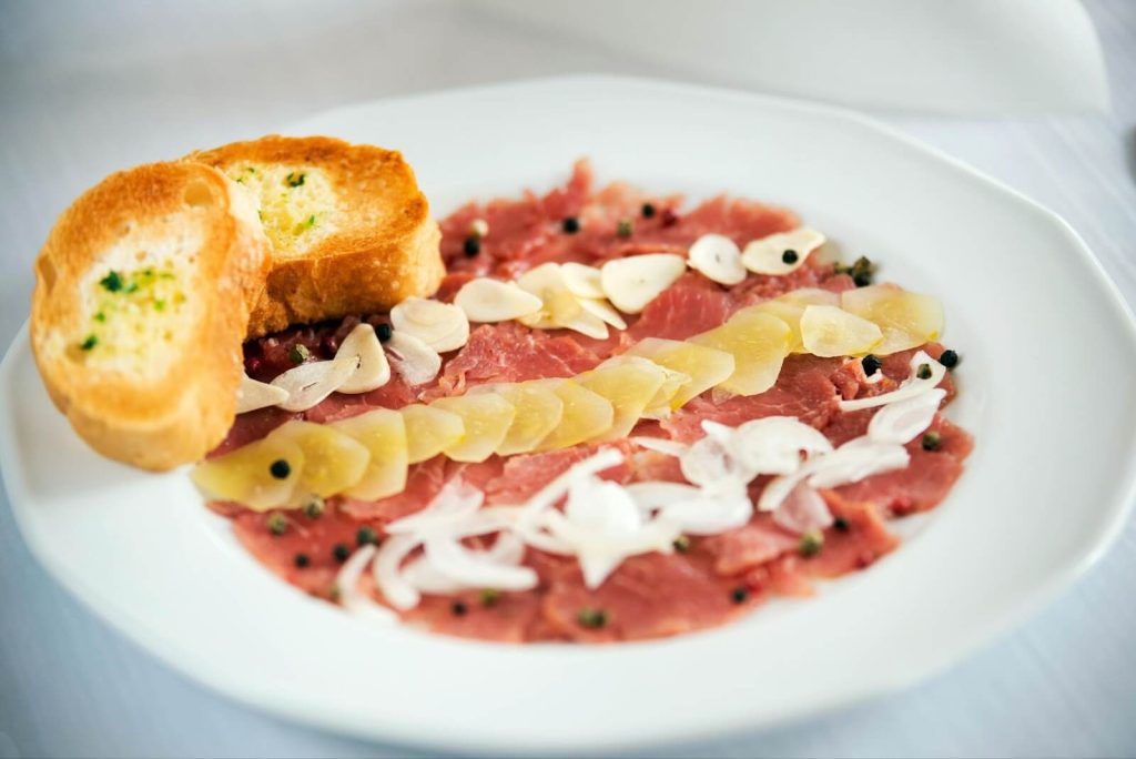 Delicious carpaccio with garlic slices and toasts.